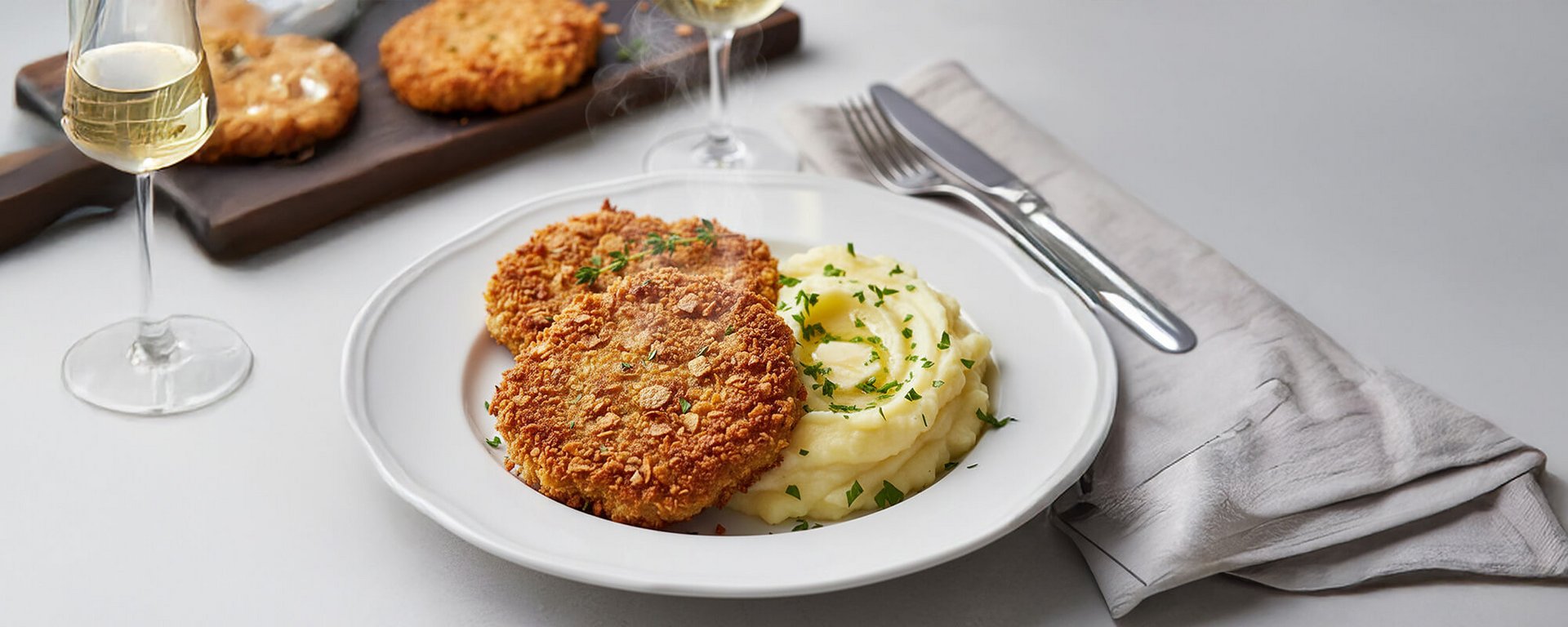 Sellerieschnitzel Rezept: servierfertiges Sellerie-Schnitzel mit cremigem Kartoffelpüree und Butterkuhle als vegetarisches Hauptgericht.