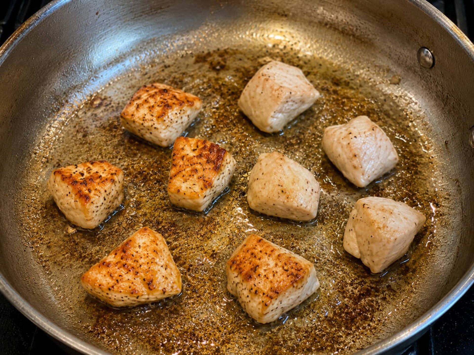 Hähnchenstücke werden in einer Pfanne kräftig angebraten