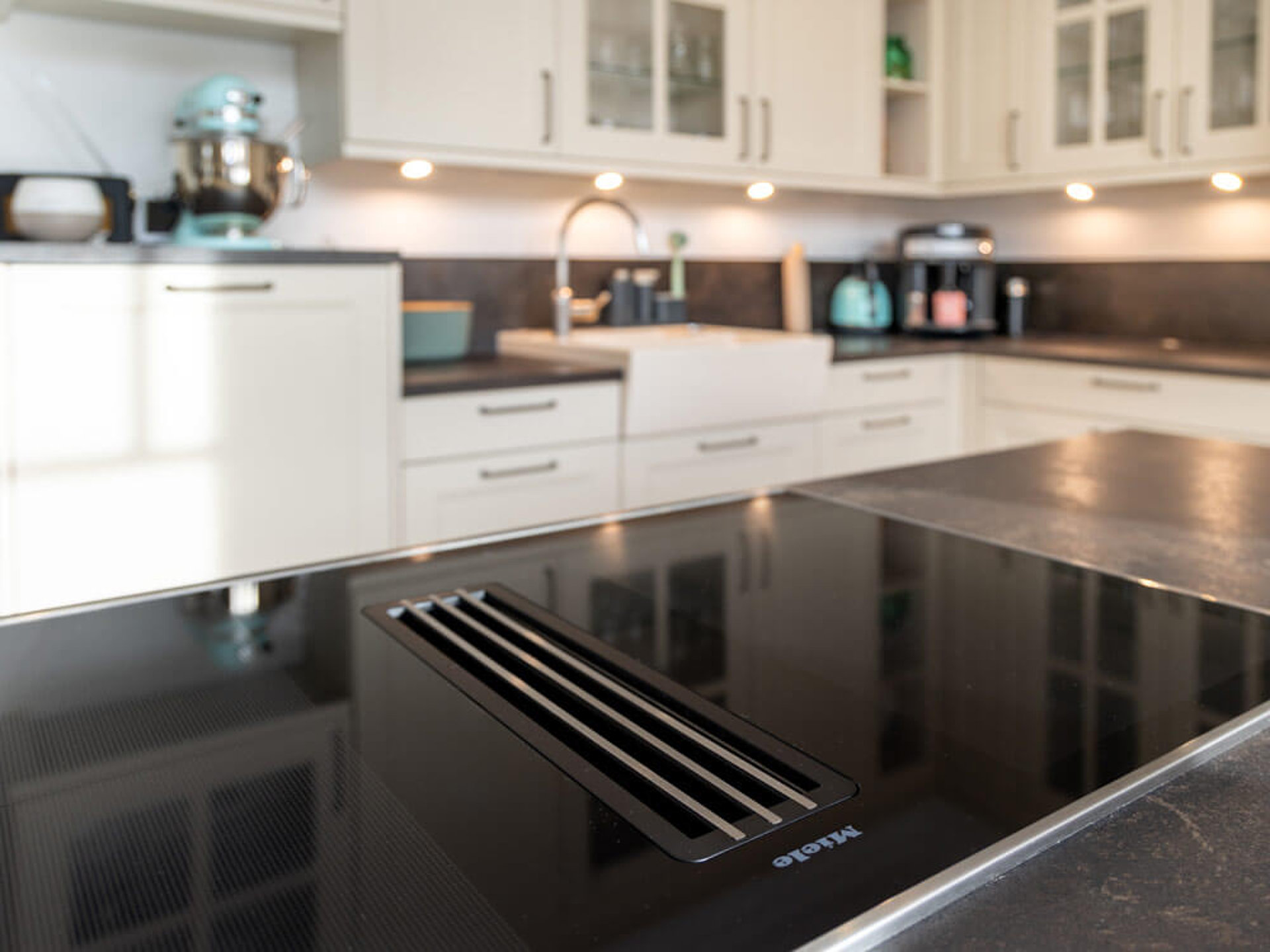 Maßgeschneiderte Küche mit Kochfeld und Spüle in unterschiedlichen, ergonomischen Arbeitshöhen von ASMO KÜCHEN.