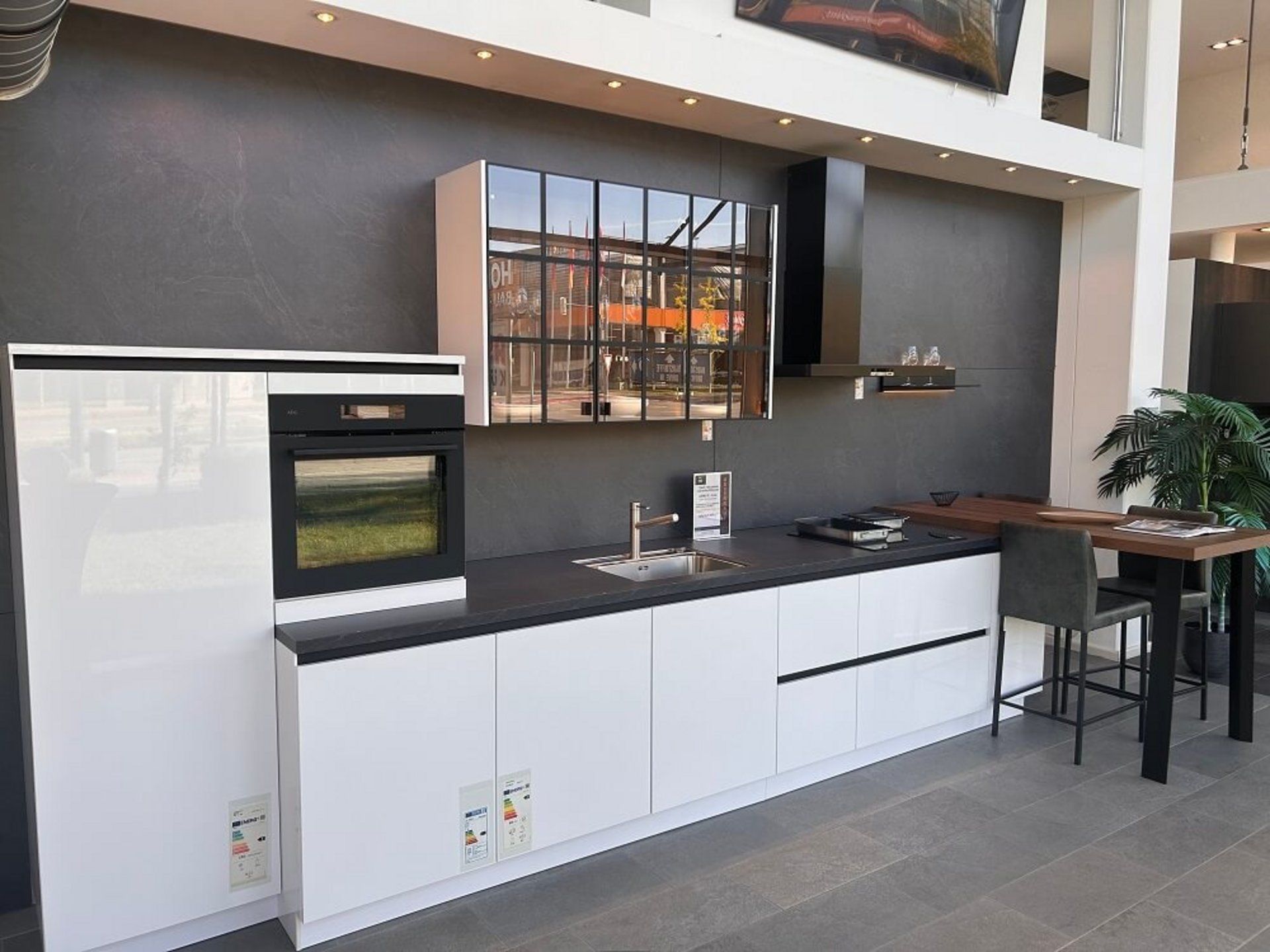 Gesamtansicht einer weißen Küchenzeile mit erhöhtem Backofen, Spüle, Kochfeld und seitlichem Ansatztisch