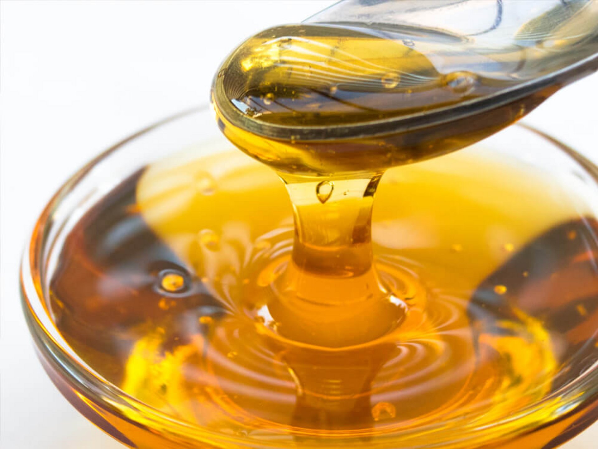 Honig tropft vom Löffel – mildert zu saure Sossen mit Wein perfekt ab.