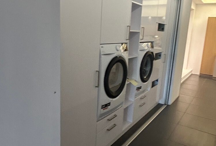 Moderner Hauswirtschaftsraum mit Waschmaschine, Trockner, Hochschränken und Stauraum bei ASMO KÜCHEN