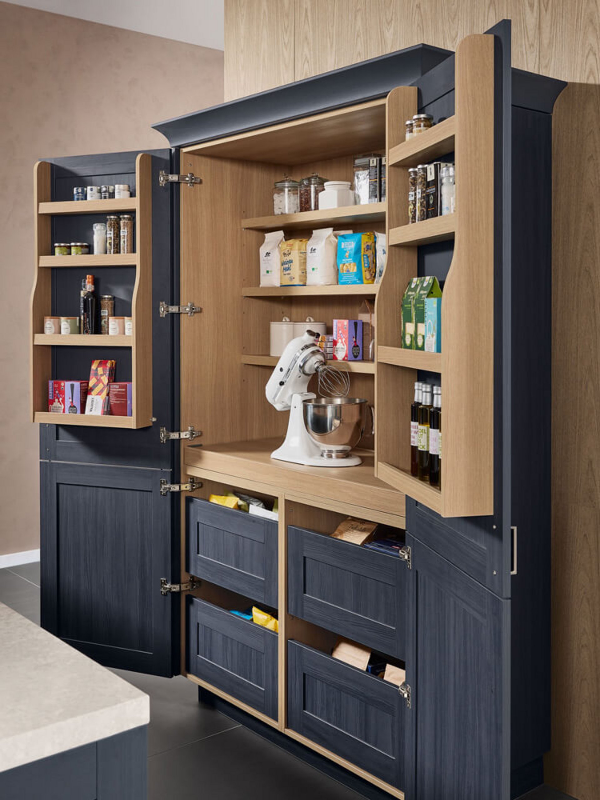 Geöffneter indigoblauer Pantry-Schrank mit Türregalen, Ablageböden, Innenauszügen und einer Küchenmaschine auf einer Stellfläche in Holzoptik.