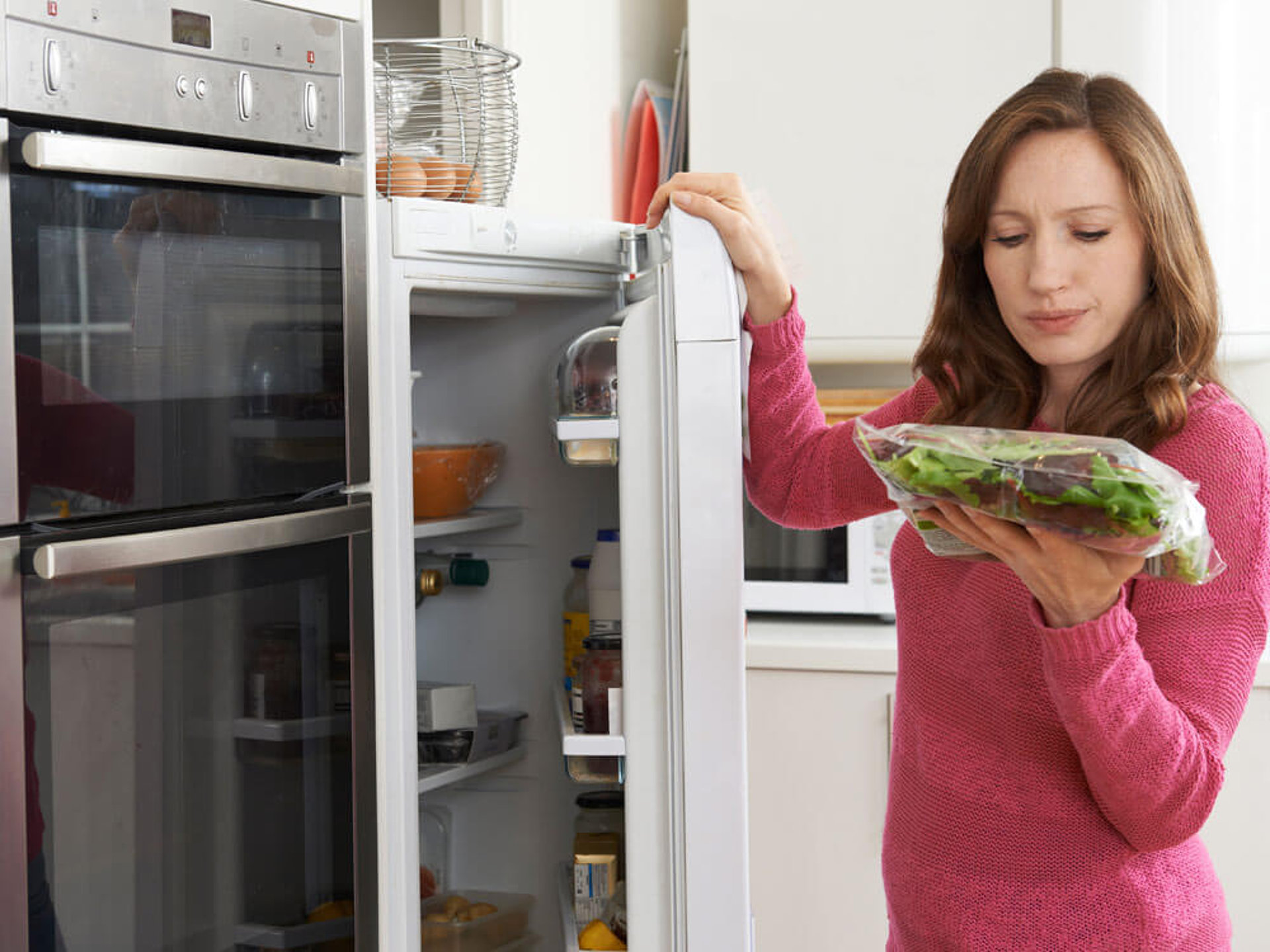 Eine Person organisiert Lebensmittel im Kühlschrank. Tipps für eine bessere Vorratshaltung und Kühlschrankorganisation.
