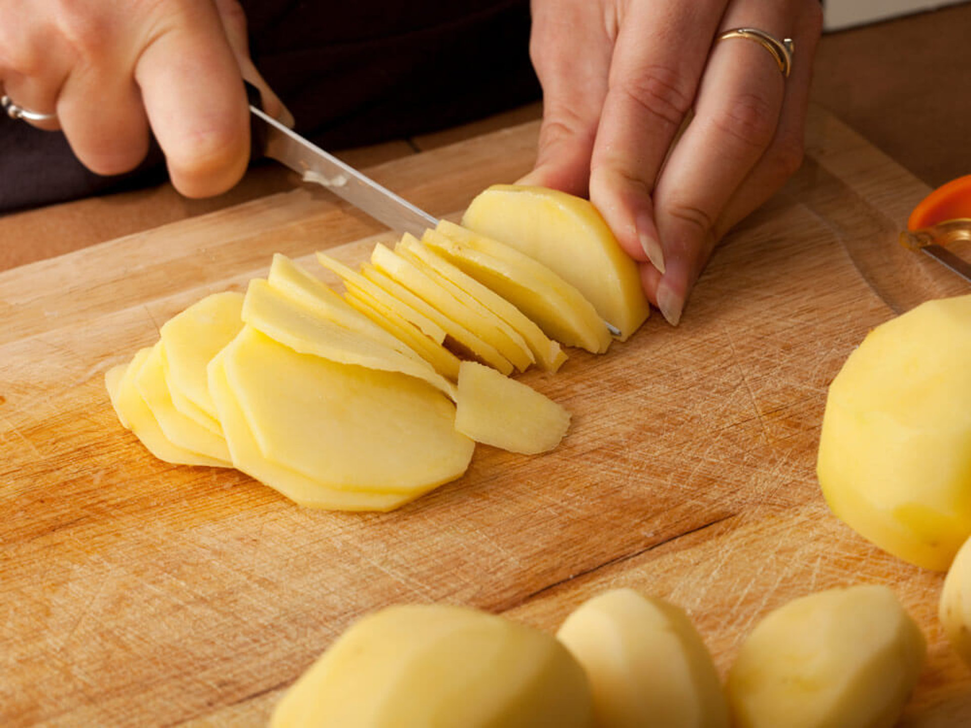 Gemüsechips selber machen – Koch schneidet rohe Kartoffeln in dünne Scheiben für extra knusprige Chips