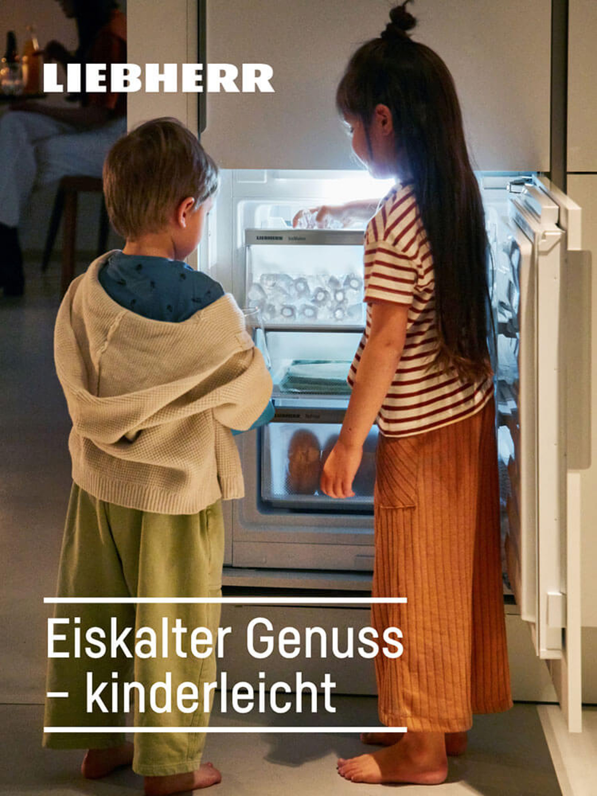 Zwei Kinder stehen vor einem geöffneten, beleuchteten Liebherr-Kühlschrank und suchen nach Eis.