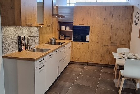 Moderne Küche Cantania in Eiche hellgrau mit weißer Unterschrankzeile, durchgehender Arbeitsplatte und Hochschrankwand im Studio von ASMO KÜCHEN Landshut.