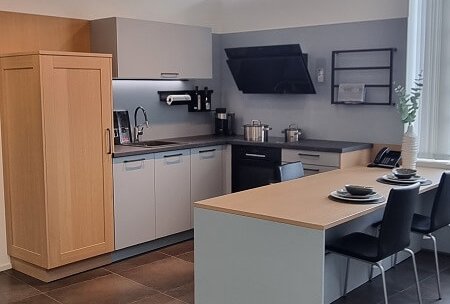 Moderne L-Küche mit Esstisch, heller Arbeitsplatte und viel Stauraum als Musterküche im Studio von ASMO KÜCHEN Landshut.