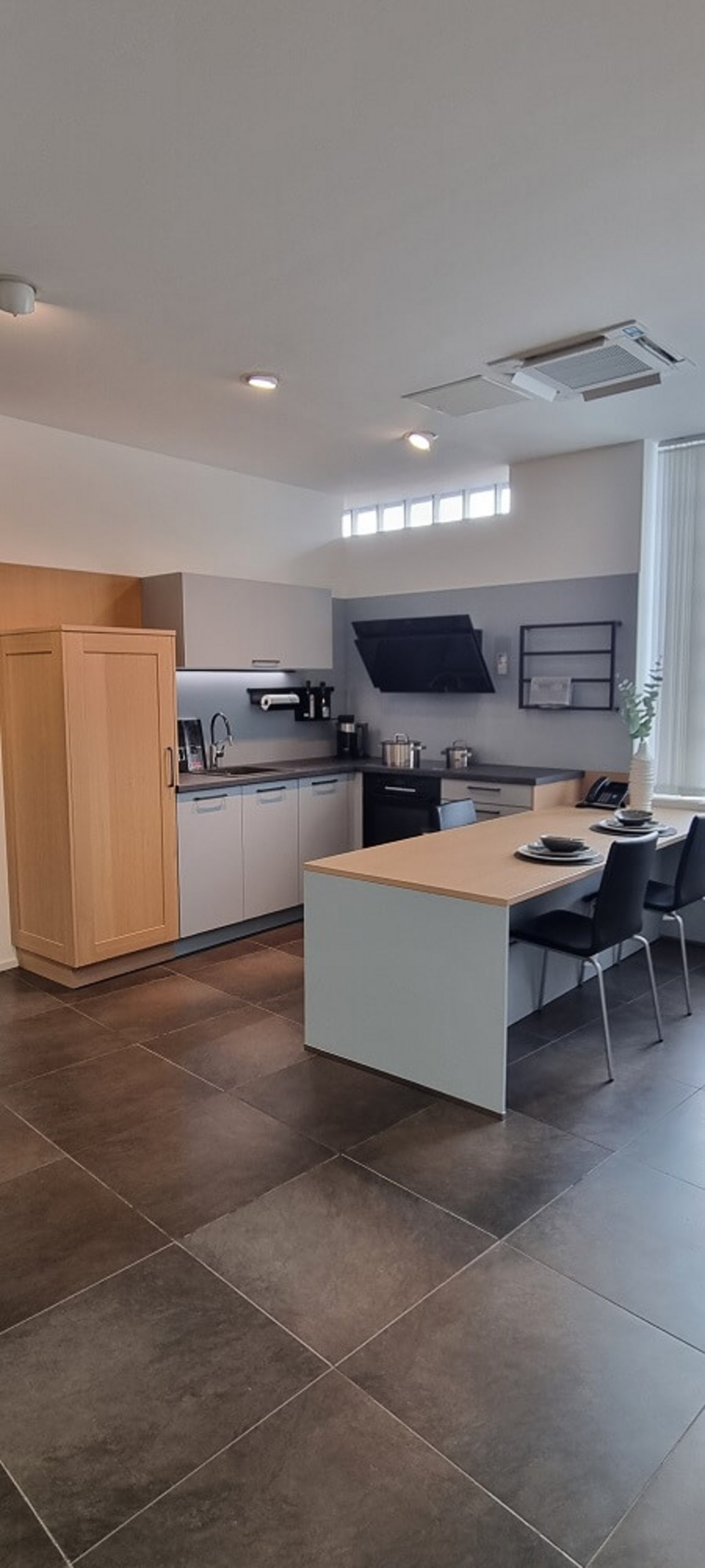 Moderne L-Küche mit Esstisch, heller Arbeitsplatte und viel Stauraum als Musterküche im Studio von ASMO KÜCHEN Landshut.