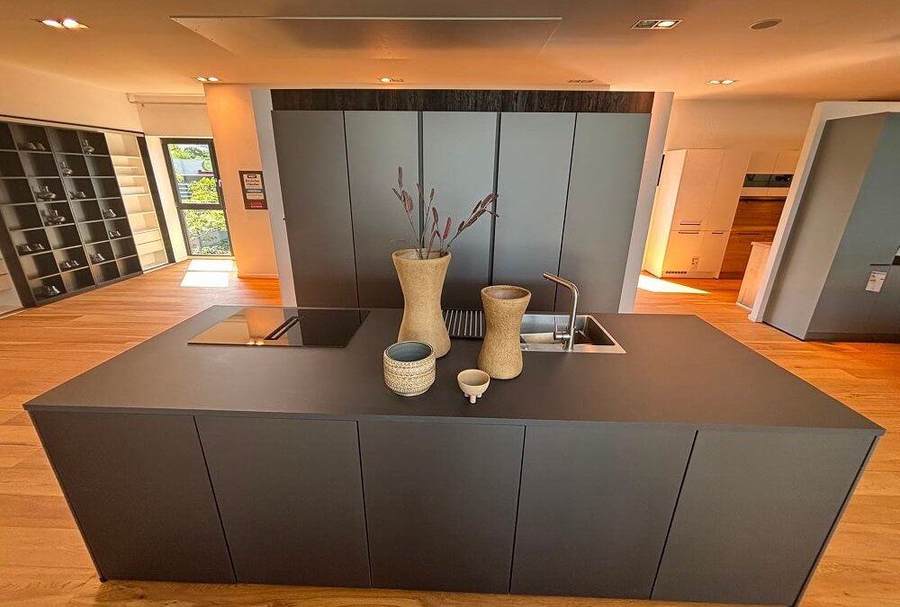 Moderne Hochschrankzeile mit Kücheninsel, dunklen Fronten und Holzoptik in der ASMO KÜCHEN Ausstellung Unterhaching
