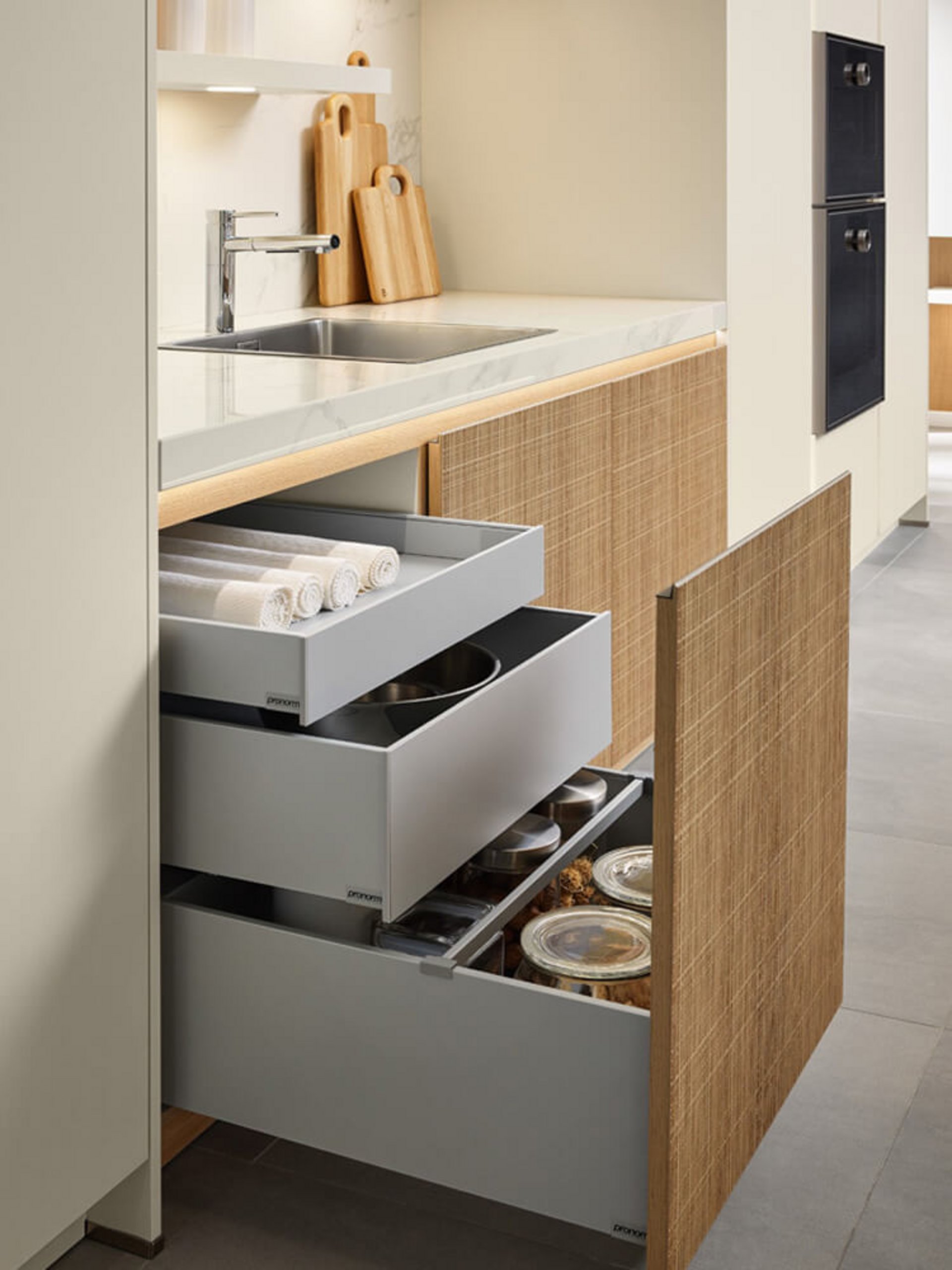Großzügige Auszüge in Titan-Optik für Stauraum in einer grifflosen Küche in Holzoptik.