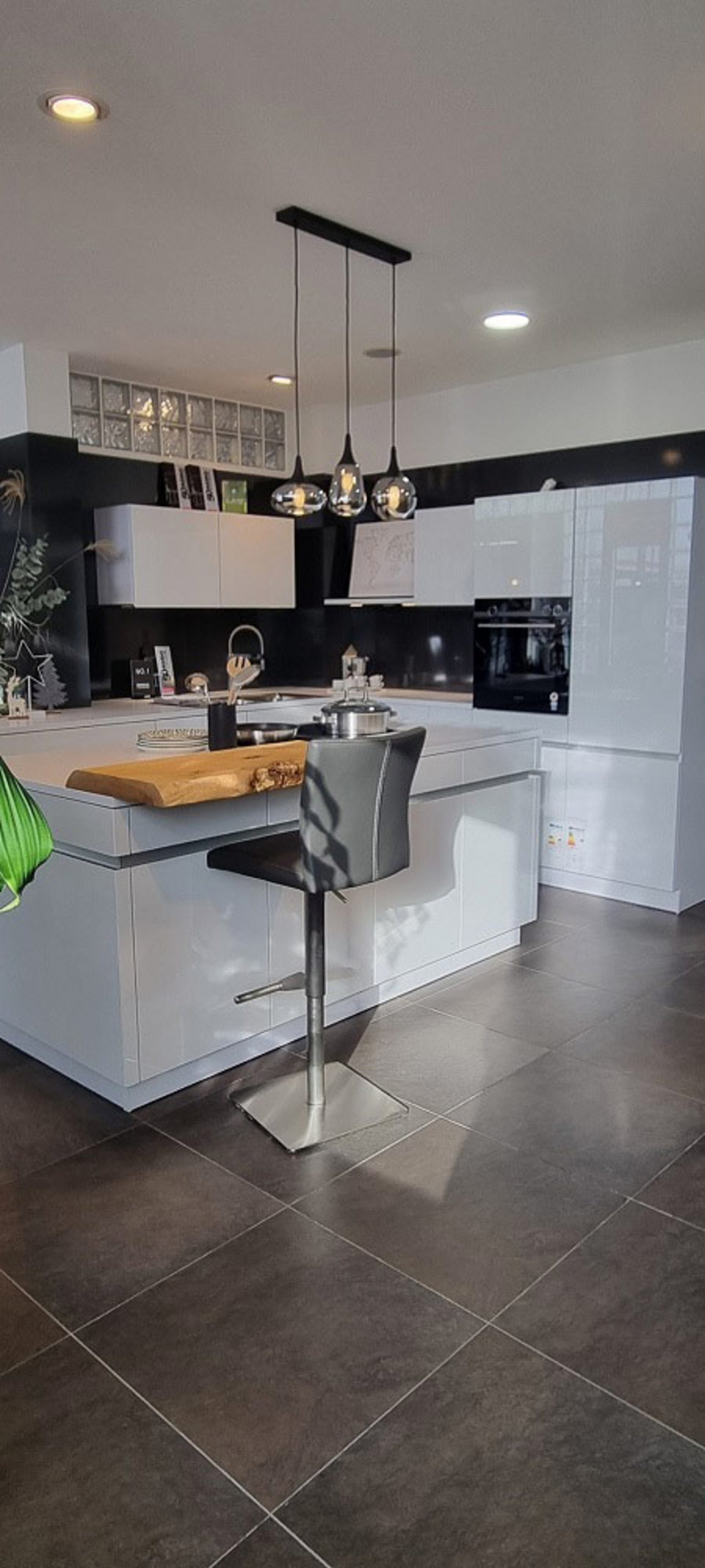 Helle grifflose L-Küche mit Kochinsel und integriertem Weinkühlschrank im ASMO Küchenstudio Landshut, Frontfarbe Arktis glänzend vom Hersteller LEICHT.