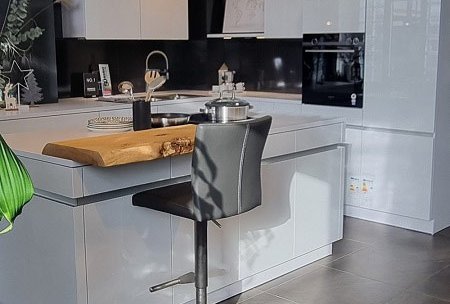 Helle grifflose L-Küche mit Kochinsel und integriertem Weinkühlschrank im ASMO Küchenstudio Landshut, Frontfarbe Arktis glänzend vom Hersteller LEICHT.