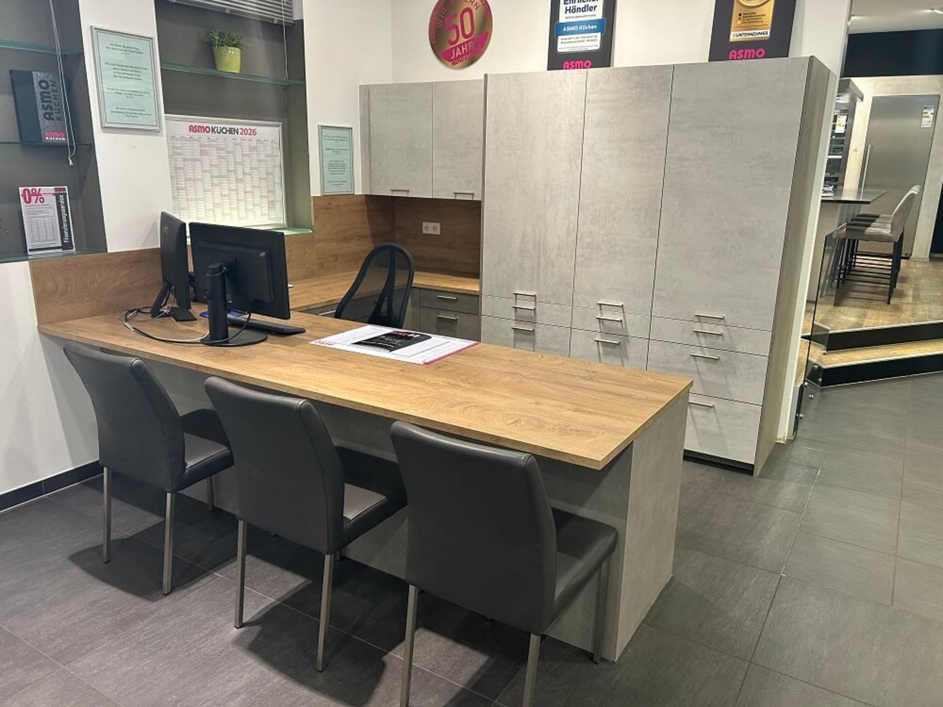 Moderner Arbeitsplatz mit langem Schreibtisch, Sitzplätzen, Stauraumschränken und Holzoptik bei ASMO KÜCHEN