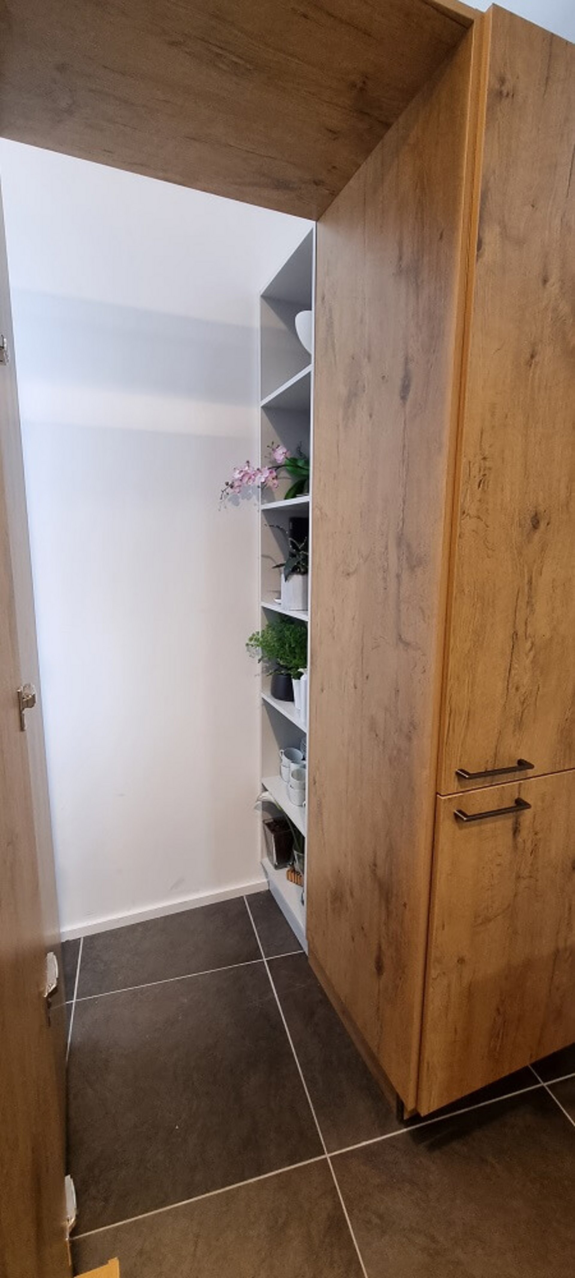 Offenes Vorratsregal der Küche Cantania in Eiche hellgrau mit dekorativen Ablagen und Hochschränken im Studio von ASMO KÜCHEN Landshut.