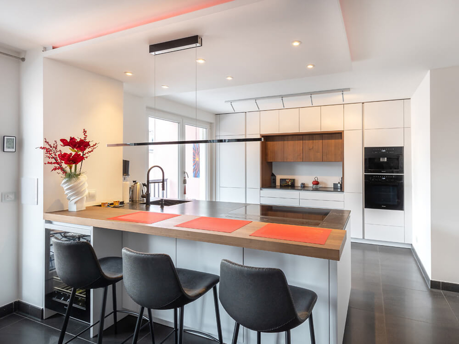 Moderne ASMO-Küche in München mit heller Kochinsel, warmen Holzakzenten und leisen Einbaugeräten in elegantem Design.