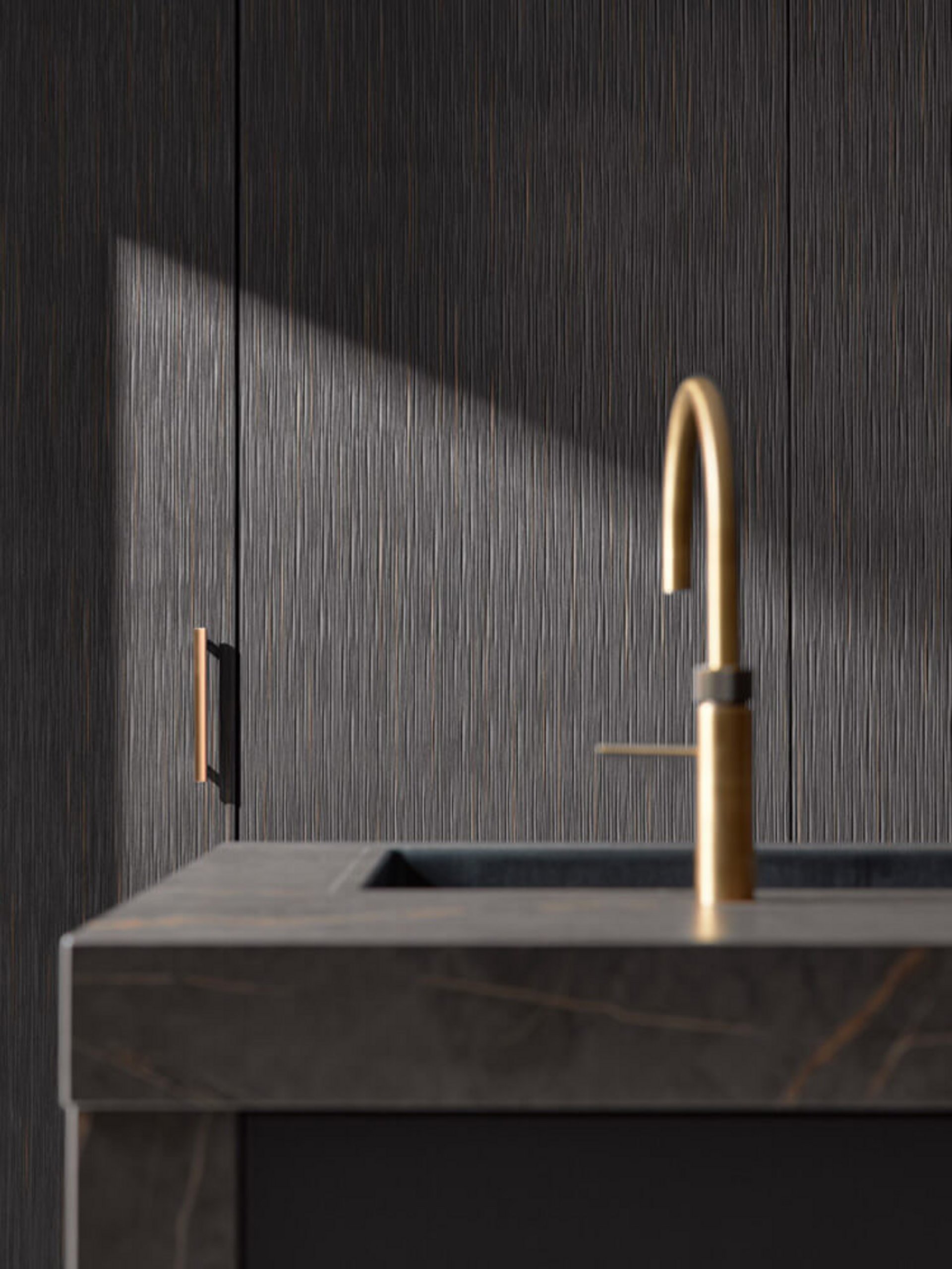 Luxusküche schwarz mit goldener Armatur auf einer dunklen Stein-Arbeitsplatte.