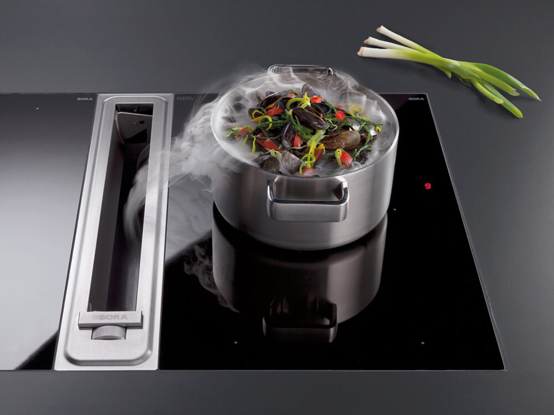 Geräuscharme Küchengeräte: BORA Kochfeld mit integriertem Dunstabzug, das Dampf seitlich direkt nach unten absaugt.