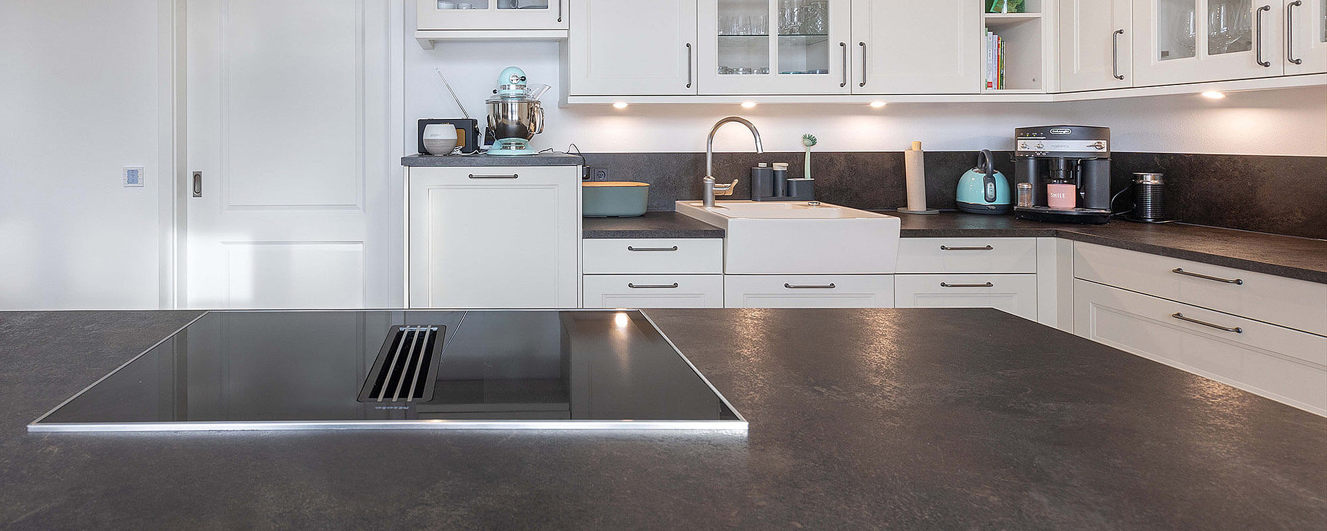 Maßgeschneiderte Küche mit Kochfeld und Spüle in unterschiedlichen, ergonomischen Arbeitshöhen von ASMO KÜCHEN.