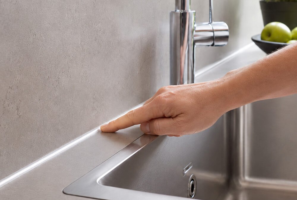 Silikonfuge an Küchenarbeitsplatte wird mit dem Finger geprüft
