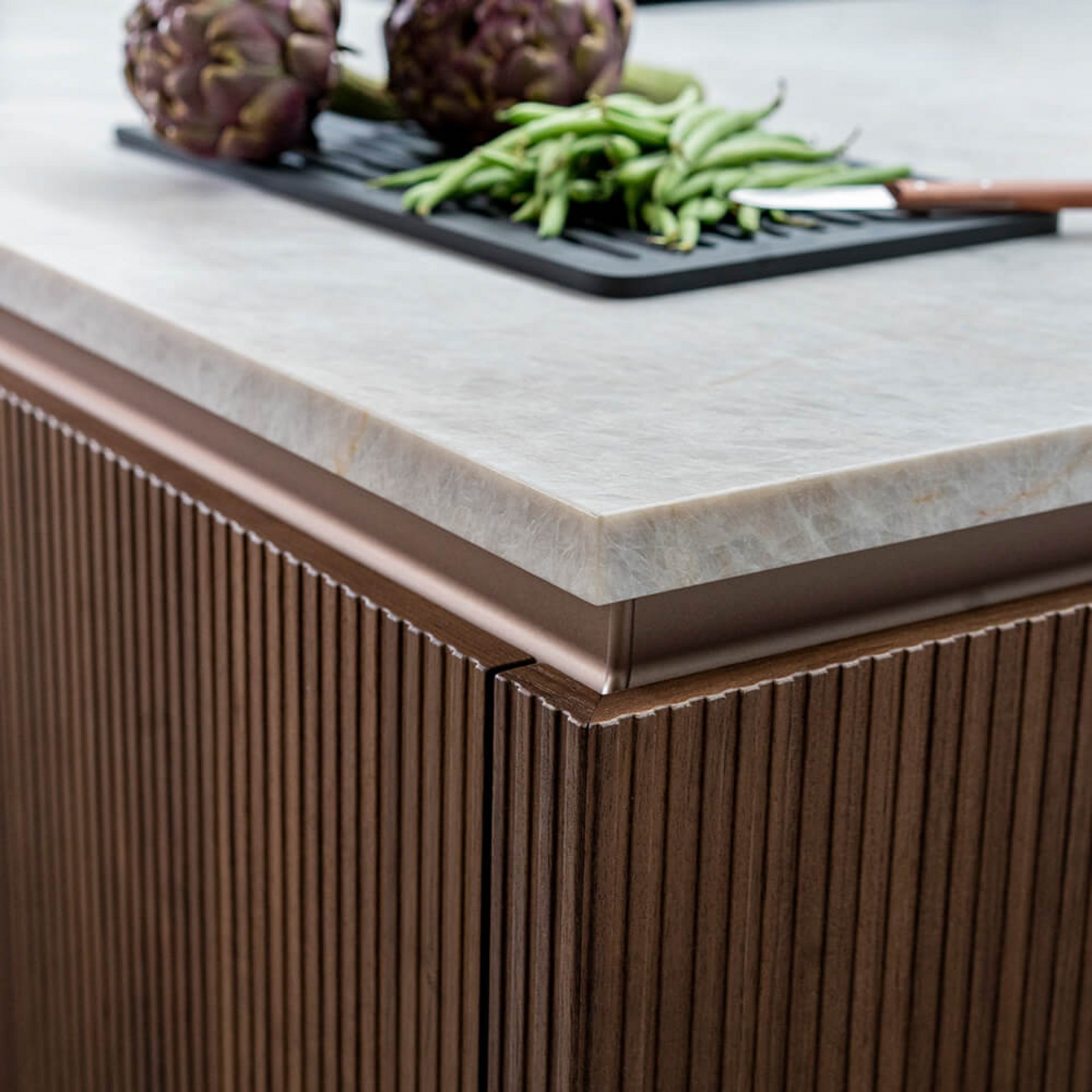 Helle Naturstein-Arbeitsplatte kombiniert mit fein gerillter Echtholzfront in der Küche.