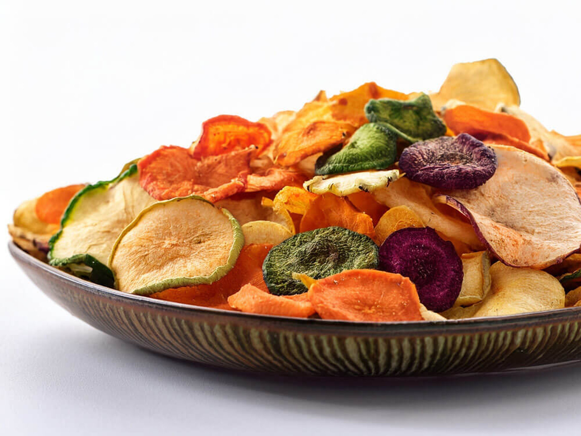 Knusprige Gemüsechips Varianten – gemischte Scheiben aus Roter Bete, Möhre und Zucchini auf brauner Platte