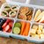 Unterteilte Brotbox mit Gemüse, Obst, Crackern und weiteren Snacks