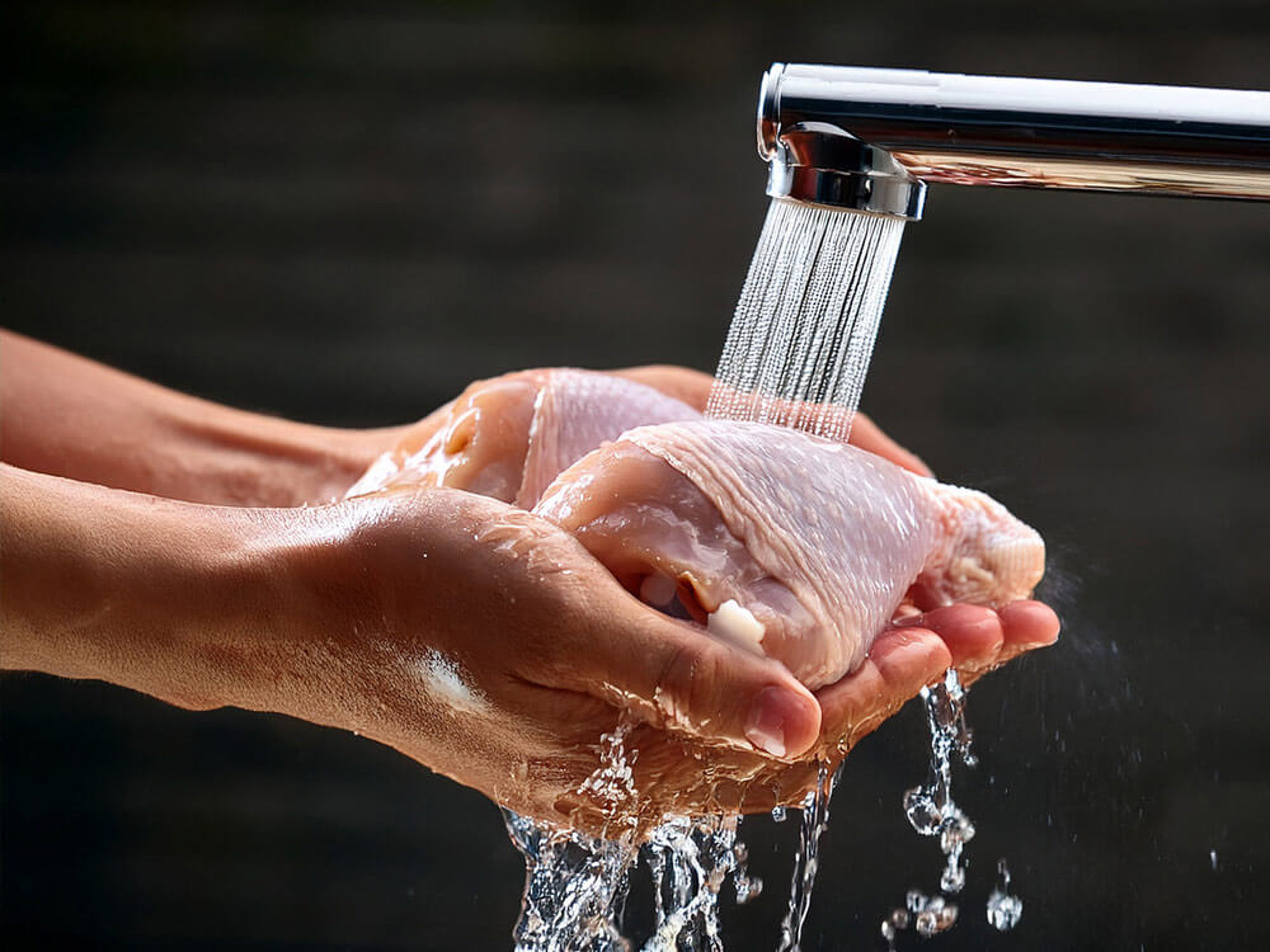 Küchenhygiene: Rohes Hähnchenfleisch unter fließendem Wasser abspülen