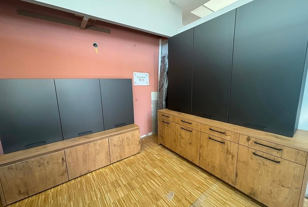 Zweiteiliger Arbeitsplatz mit dunkler Rückwand, Arbeitsfläche und Holzoptik in der ASMO KÜCHEN Ausstellung Unterhaching