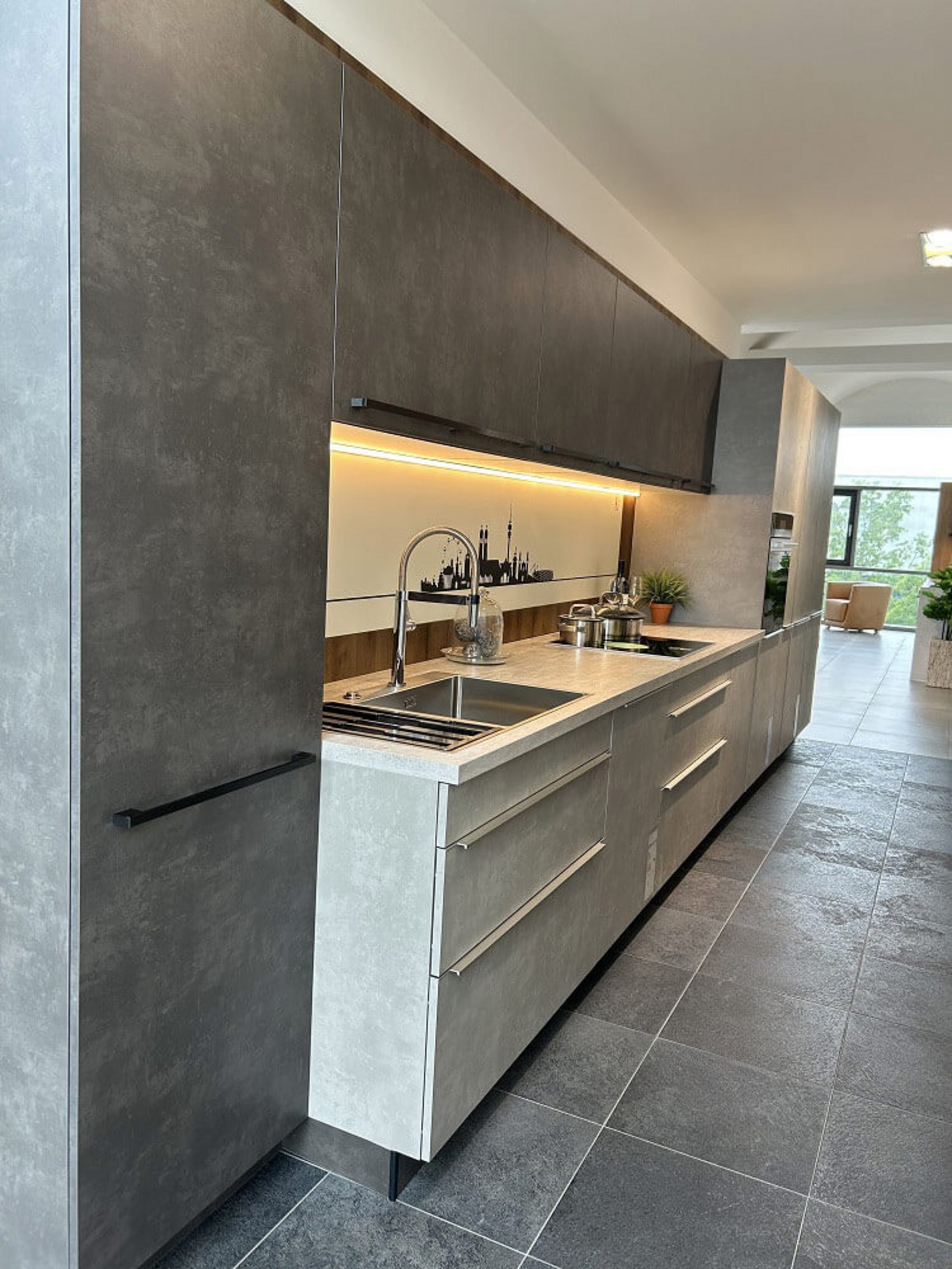 Moderne ASMO KÜCHEN Küchenzeile mit grauen Betonfronten, Holzdetails, Spüle und beleuchteter Nischenrückwand