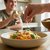 Schale mit Pasta, Cherrytomaten, Parmesan und Basilikum auf einem Tisch