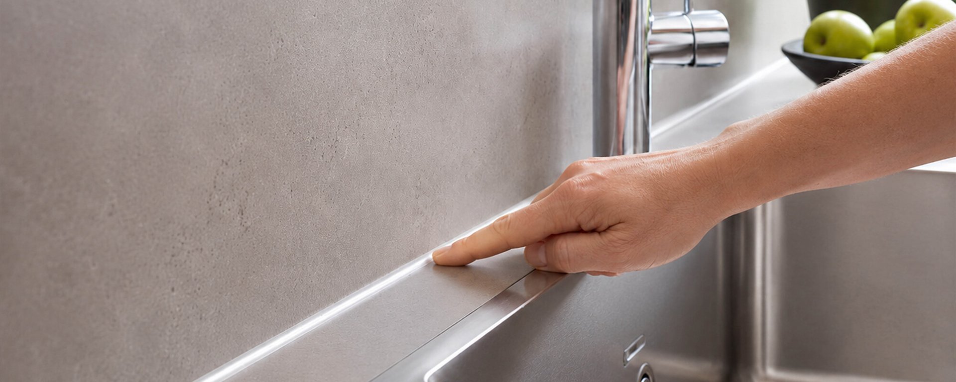 Hand kontrolliert Silikonfugen in der Küche im Bereich der Spüle