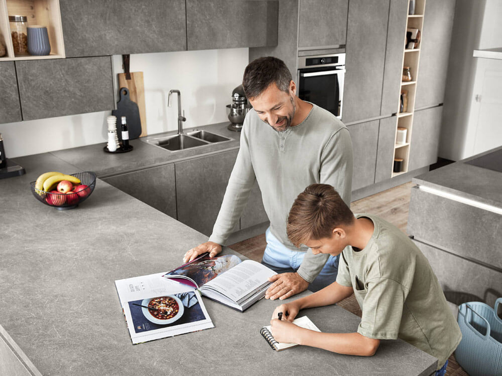 Vater und Kind kochen in einer modernen Anti-Fingerprint Küche mit Arbeitsplatten aus StoneArt. ASMO KÜCHEN.