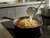 Pasta wird mit Parmesan und Cherrytomaten in einer Pfanne vermengt