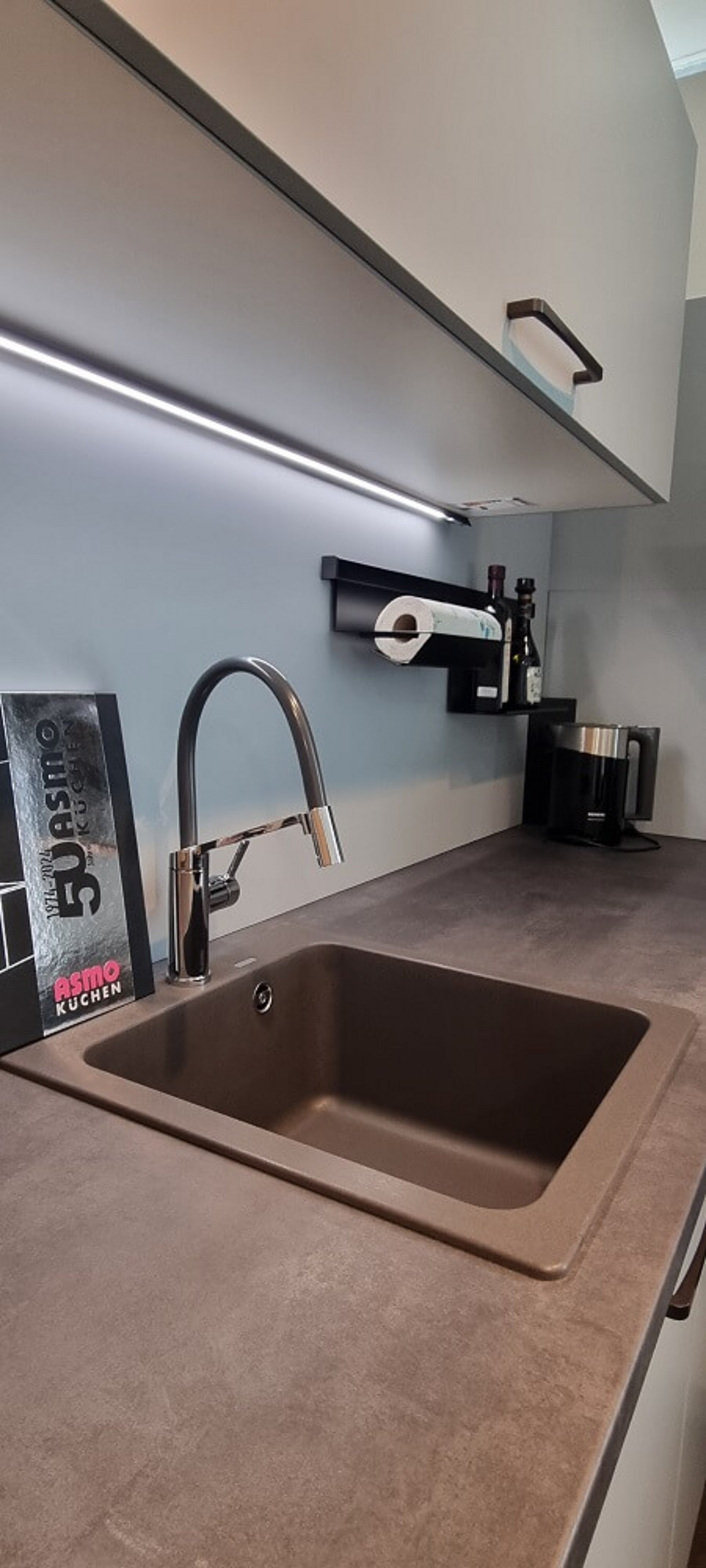 Detailansicht der modernen L-Küche mit Hängeschränken, Hochschrankbereich und großzügiger Arbeitsfläche in der Ausstellung von ASMO KÜCHEN Landshut.